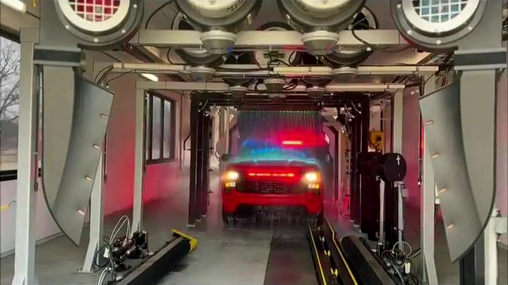 A red pickup rolls through the Tiger Xpress tunnel under the light arches and a rainbow curtain of water