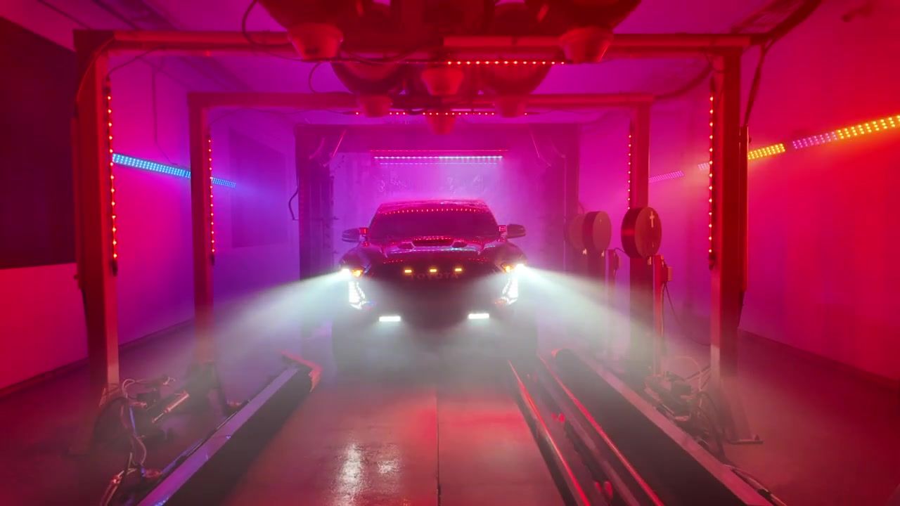 A pickup's headlights cut through pink and red fog inside the haunted tunnel