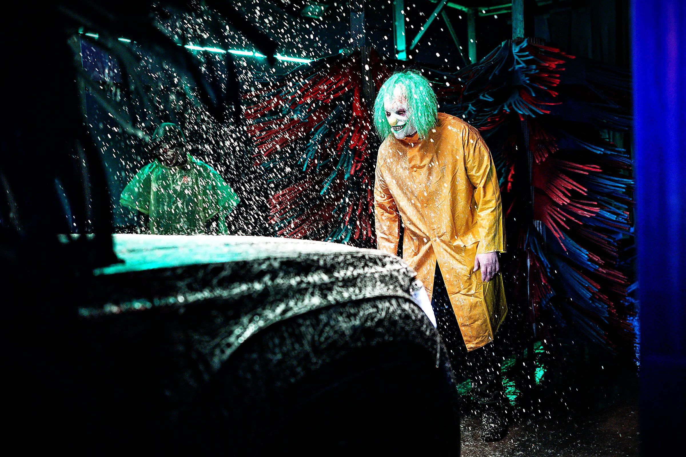 A Haunted Car Wash actor in a yellow slicker looms over a car in the tunnel