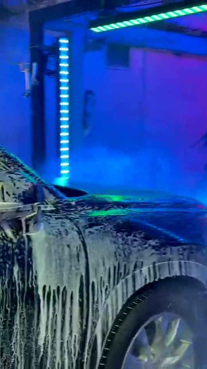 A foam-covered SUV passes under blue and purple LED arches