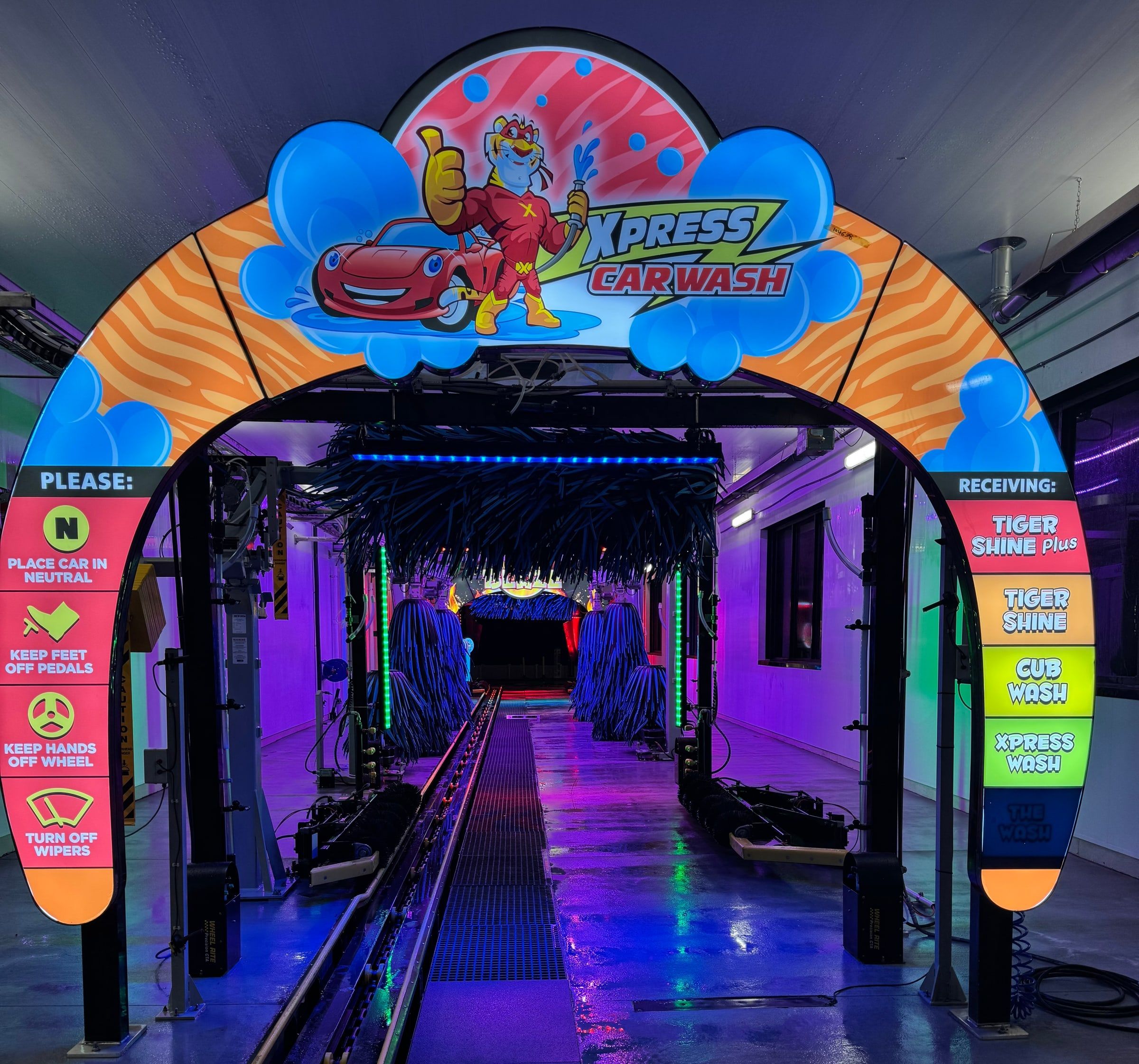 Looking through the Tiger Xpress entrance arch at the blue wrap brushes, with lane signs listing each wash