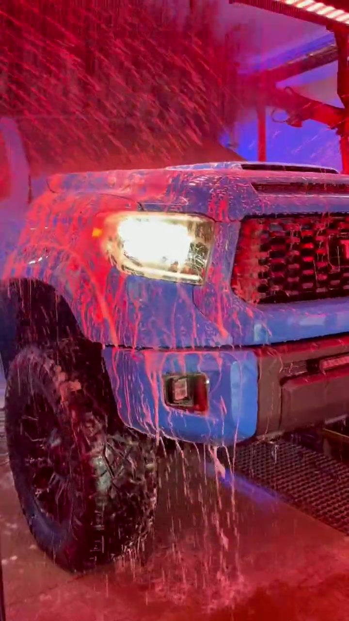 A blue Toyota Tundra rolls through the tunnel under pink foam and red and rainbow lights